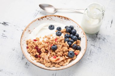 Bowl of granola with yogurt and fresh blueberries for healthy breakfast clipart