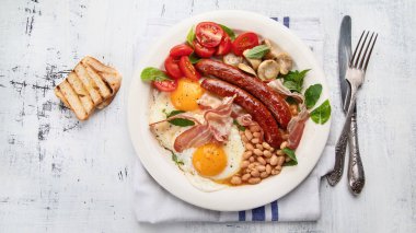 Sahanda yumurta, sosis, fasulye, mantar ve pastırma tam geleneksel İngiliz kahvaltısı. Üstten görünüm