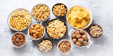 Farklı türde çerez, cips, fındık ve kase tablo arka plan üzerinde patlamış mısır