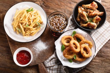 Fast food aperatifler - soğan, patates ve tavuk kanatları. Amerikan Mutfagi. Üstten görünüm