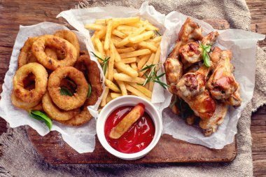 Fast food aperatifler - soğan, patates ve tavuk kanatları. Düz yatıyordu