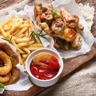 Fast food aperatifler - soğan, patates ve tavuk kanatları. Amerikan Mutfagi. 