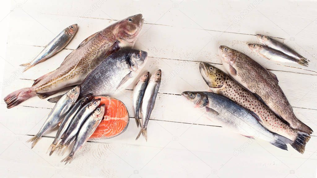 Fresh fish and seafood on white wooden background. Healthy eating. Top view 