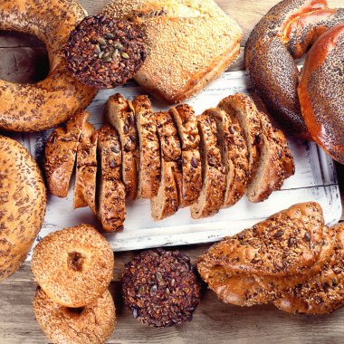 Taze pişmiş kepekli ekmek rustik ahşap masa üzerinde karışık.