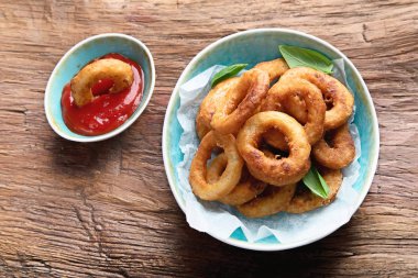 Ahşap arka plan üzerinde çıtır çıtır kızarmış soğan halkası