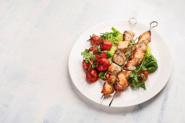 Domates ve yeşil beyaz tabakta tavuk şiş