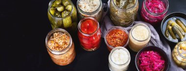 Fermented preserved food. Marinated pickles vegetables in glass jars. Panorama clipart