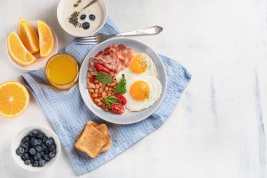 Tabak kızarmış yumurta, pastırma, fasulye, portakal suyu ve tost ile kahvaltı. Kopya alanı ile üstten görünüm