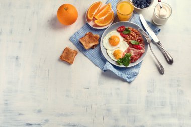 Tabak kızarmış yumurta, pastırma, fasulye, portakal suyu ve tost ile kahvaltı. Kopya alanı ile üstten görünüm