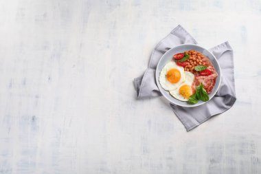 Tabak kızarmış yumurta, pastırma, fasulye, portakal suyu ve tost ile kahvaltı. Kopya alanı ile üstten görünüm