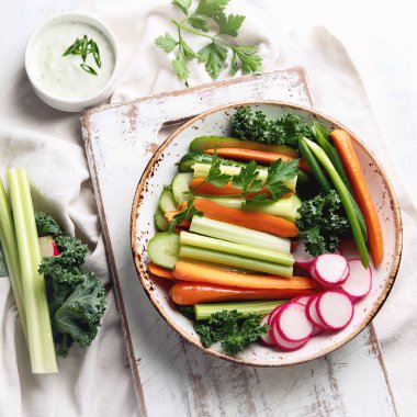 soslu beyaz arka plan üzerinde renkli sağlıklı sebze çerez tabağı içinde üzerinde üstten görünüm