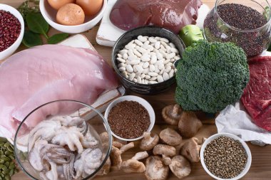 demir yönünden zengin besinler karaciğer, et, yumurta, mercimek, fasulye, brokoli, mantar, quinoa ve deniz ürünleri ahşap tablo olarak