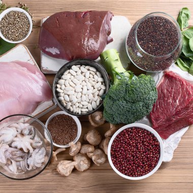 demir yönünden zengin besinler karaciğer, et, yumurta, mercimek, fasulye, brokoli, mantar, guinoa ve deniz ürünleri ahşap masa üzerinde olarak. Sağlıklı beslenme kavramı