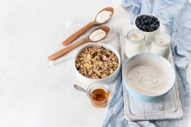 Taze meyve, granola ve bal ile beyaz tabloda taze yoğurt kavanoz.