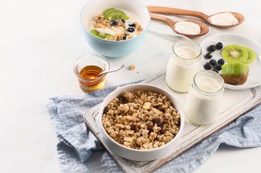 Taze meyve, granola ve bal ile beyaz tabloda taze yoğurt kavanoz.