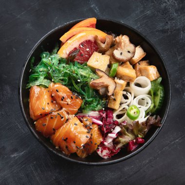 üstten görünüm kase lezzetli somon, quinoa, sebze, meyve ve tofu karanlık masa üzerinde