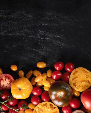 Çeşitli boyut ve renkleri ile kopya alanı siyah arka plan üzerinde renkli taze domates. 
