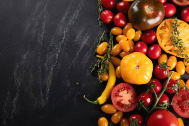 Çeşitli boyut ve renkleri ile kopya alanı siyah arka plan üzerinde renkli taze domates. 