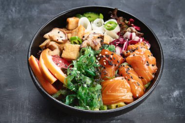 Poke bowl with salmon, quinoa, vegetables, fruits and tofu on dark background clipart