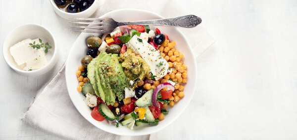 Чаша свежего салата с горохом, фета, оливки и авокадо на скатерти
.