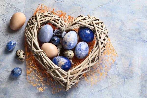 Easter eggs in heart shaped nest. Top view with copy space. Blue Easter background