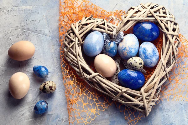 Easter eggs in heart shaped nest. Top view. Blue Easter background