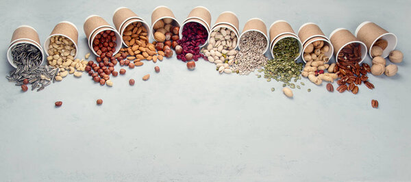Different types of Nuts in ecofriendly cups high in vegan protein, vitamins and antioxidants for immune system boosting. Ecofriendly concept. Panorama, banner  with copy space