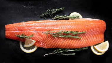 Taze balık. Siyah arka planda çiğ somon balığı. Üst manzara, düz uzanma 