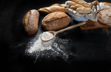 Fotokopi alanı olan siyah arka planda taze ekmek ve çörekler. Yukarıdan görüntüle. 