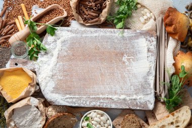 Farklı tipte yüksek karbonhidratlı yiyecekler. Gri arkaplanda iyi karbonhidrat kaynakları seçimi. Üst manzara, düz uzanma.