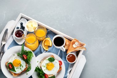 Geleneksel Amerikan kahvaltısı gri arka planda beyaz ahşap tepside servis edilir. Üst görünüm, düz görünüm, kopyalama alanı.