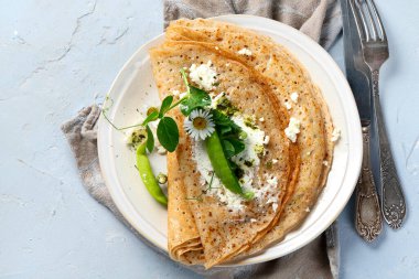 Tatlı olmayan iştah açıcı krepler. Gri arka planda pesto ve ricota ile. Lezzetli krepler, ince krepler. Lezzetli bir kahvaltı. Üst görünüm, telif alanı olan düz uzanma.