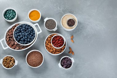 Gri arka planda çeşitli abur cuburlar. Sağlıklı organik yiyecekler. Temiz yemek. Üst görünüm, kopyalama alanı olan düz uzanma.