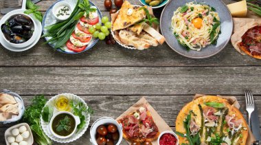 Kırsal ahşap masada iştah açıcı klasik İtalyan mutfağı. Farklı pizza, makarna, aperatif ve capreze çeşitleri. Sağlıklı ev yemekleri. Üst görünüm, telif alanı olan düz uzanma.