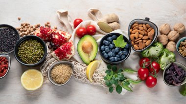 Beyaz ahşap arka planda sağlıklı yiyecek seçimi. Taze meyve, süper yiyecekler, sebzeler. Yüksek miktarda antioksidan, vitamin, mineral ve lif. Üst görünüm 