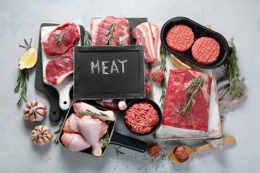 Gri arka planda çiğ et çeşitleri. Üst görünüm