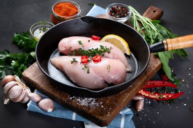 Çiğ tavuk göğsü ve tava tabağında sos, ahşap bir tahtanın üzerinde sebzeler..