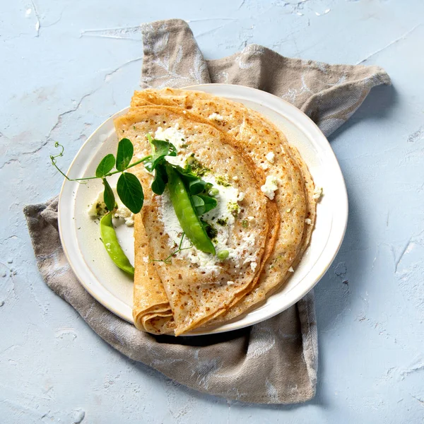 Tatlı olmayan iştah açıcı krepler. Gri arka planda pesto ve ricota ile. Lezzetli krepler, ince krepler. Lezzetli bir kahvaltı. Üst manzara, düz uzanma