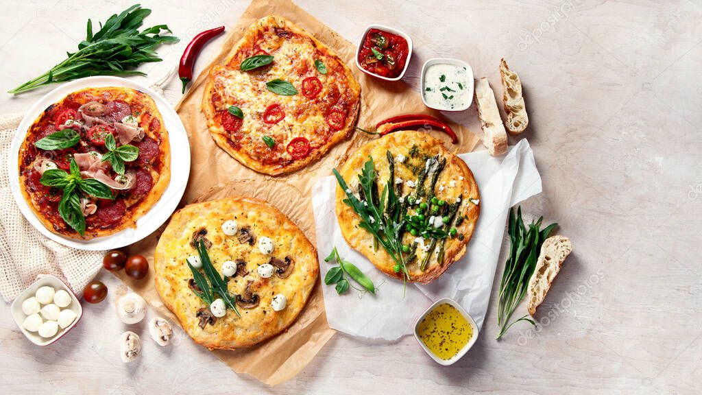 Various kinds of Italian pizza on rustic wooden table, top view, wide composition. Freshly prepared pizza, baked with herbs and vegetables, seafood, meat. Top view, flt lay with copyspace