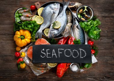 Kırsal ahşap arka planda taze balık ve deniz ürünleri, baharatlar ve sebzeler. Dengeli beslenme ve pişirme konsepti