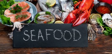 Kırsal ahşap arka planda taze balık ve deniz ürünleri, baharatlar ve sebzeler. Dengeli beslenme ve pişirme konsepti