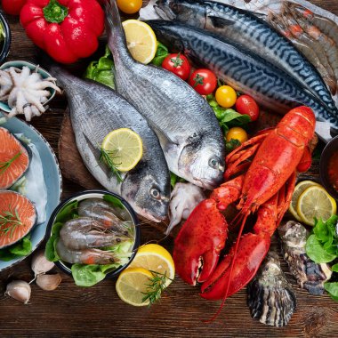 Kırsal ahşap arka planda taze balık ve deniz ürünleri, baharatlar ve sebzeler. Dengeli beslenme ve pişirme konsepti