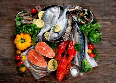 Kırsal ahşap arka planda taze balık ve deniz ürünleri, baharatlar ve sebzeler. Dengeli beslenme ve pişirme konsepti