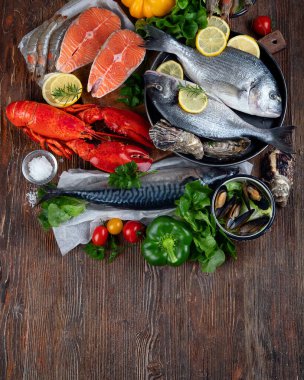 Kırsal ahşap arka planda taze balık ve deniz ürünleri, baharatlar ve sebzeler. Dengeli beslenme ve pişirme konsepti