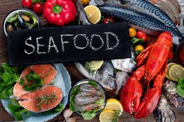 Kırsal ahşap arka planda taze balık ve deniz ürünleri, baharatlar ve sebzeler. Dengeli beslenme ve pişirme konsepti