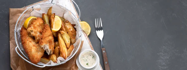 British traditional cuisine fish and chips. Served with mashed peas and different sauces. Top view, copy space.