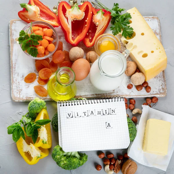 Foods high in vitamin A. Natural products rich in vitamin A. Important for normal vision, the immune system, and reproduction. Copy space, Top view, chalkboard, notebook.