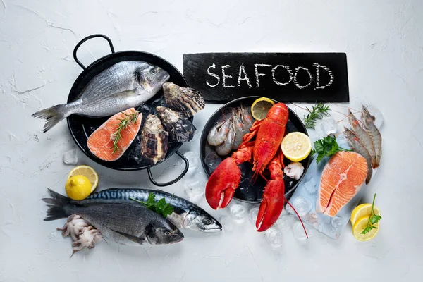 Assortment of fresh raw fish and seafood. Healthy and balanced diet or cooking concept. Top view, copy space, chalkboard