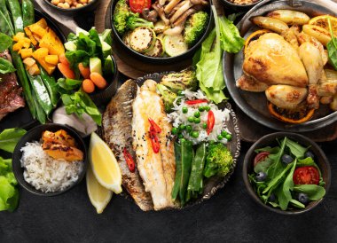 Siyah arka planda çeşitli et yemekleri, balık, salata, garnitür ve atıştırmalıklar. Üst Manzara. Boşluğu kopyala.