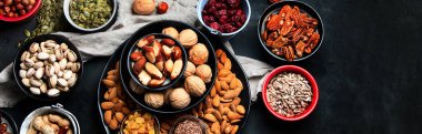 Siyah arka planda fındık, tohum ve kurutulmuş meyve. Bağışıklık sistemini güçlendirmek için yüksek miktarda vegan protein, vitamin ve antioksidan içeren yiyecekler. Kopyalama alanı olan Panorama